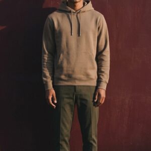 Homme portant un sweat à capuche beige en molleton bio et un pantalon vert